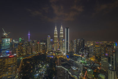 Illuminated buildings in city against sky at night