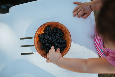 Directly above shot of baby girl picking blackberry from bowl