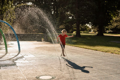 Boy playing with umbrella against trees