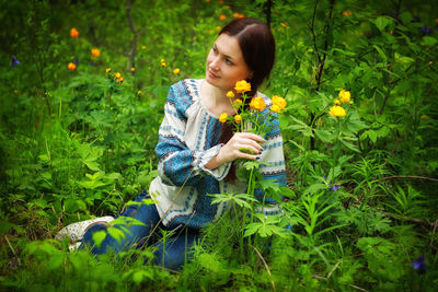 Happy girl holding flower against plants