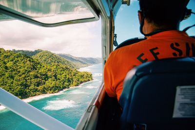 Rear view of pilot flying airplane over sea