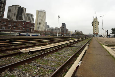 Railroad tracks amidst buildings in city against sky