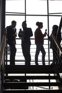 Multiracial male and female colleagues discussing with each other on staircase in corporate event