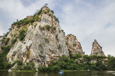 Rock formation by trees against sky