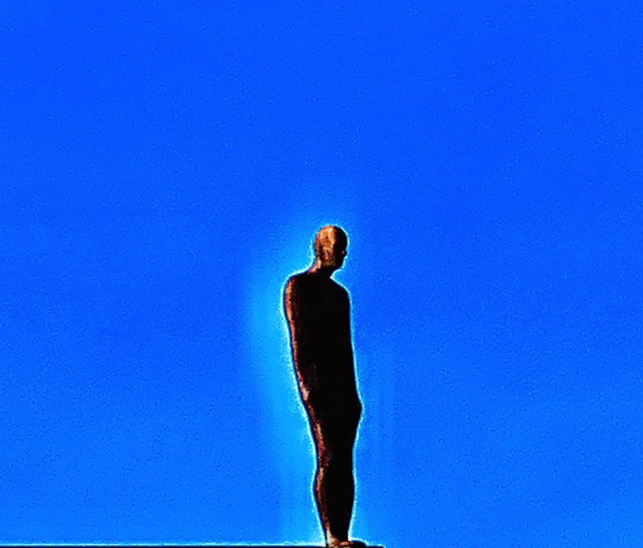 LOW SECTION OF WOMAN STANDING AGAINST CLEAR BLUE SKY