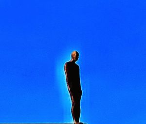 Low angle view of woman standing against blue sky