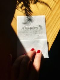 Cropped hand holding paper with text on wooden table