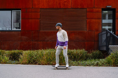 Full length of young man standing on footpath