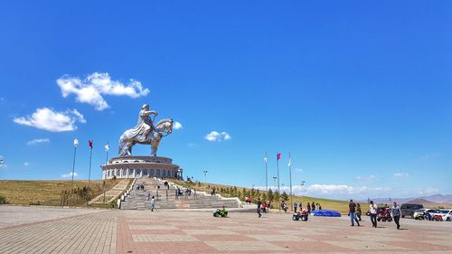 Group of people at statue against blue sky