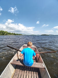 Boy in blue with life jackets at legs floats on vessel boat and hard woarking. boat sail on lake