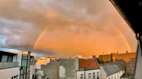Panoramic view of rainbow over buildings against sky during sunset