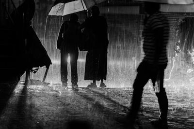 People walking on road in city during rainy season