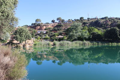 Reflection of trees and buildings in lake against clear sky