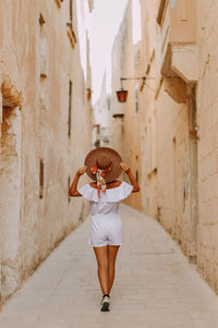 Full length of woman standing amidst buildings in silent city mdina in malta