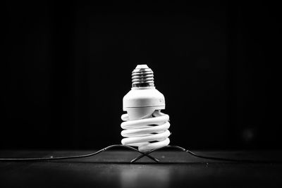 Close-up of light bulb on table against black background