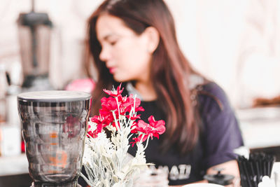 Close-up of woman with red flower on table