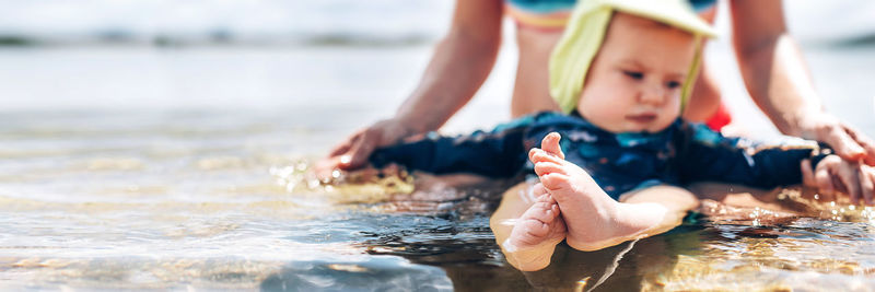 Midsection of woman with baby in sea