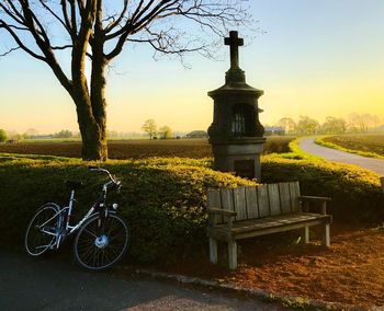 Bicycle on field against sky at sunset