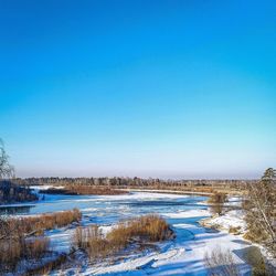 Scenic view of lake against clear blue sky during winter