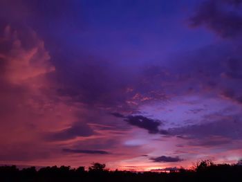 Low angle view of silhouette trees against dramatic sky