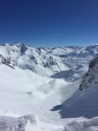 Scenic view of snow covered mountains against blue sky