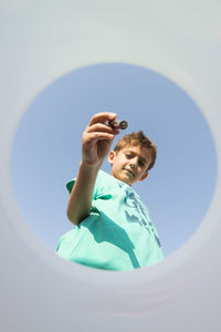 Low angle view portrait of boy holding battery