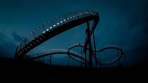 Low angle view of silhouette rollercoaster against sky at dusk