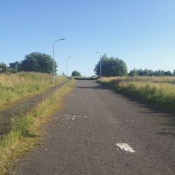 Road amidst field against clear sky