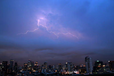 Lightning over illuminated buildings in city at night