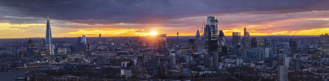 Illuminated cityscape against sky during sunset