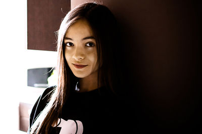 Portrait of young woman standing by wall