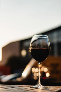 Glass with red wine on the wooden table at sunset