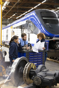 Smiling trainees discussing with engineer in manufacturing industry