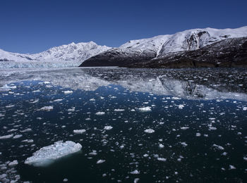 Snow floating on river by snowcapped mountains