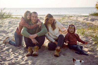 Portrait of friends sitting on rock at beach