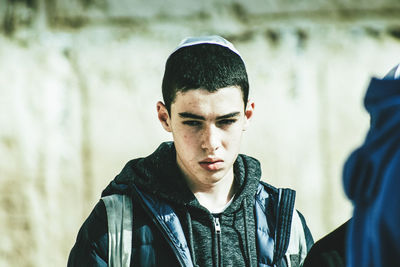 Portrait of young man with arms raised standing outdoors