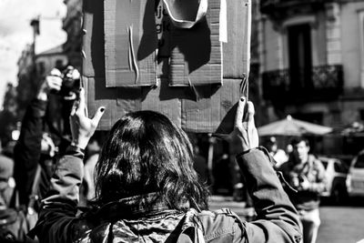 Rear view of woman holding information sign during protest in city