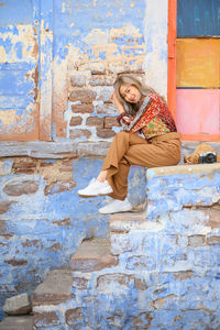 Portrait of woman sitting against wall