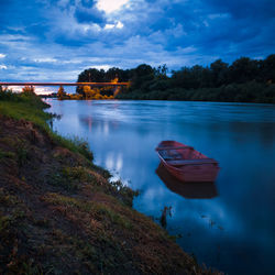 Landscape with moored boat in sava river during overcast evening at blue hour 