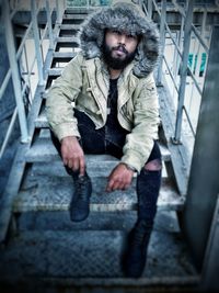 Full length portrait of young man on staircase in city