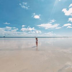 Rear view of woman walking at beach against sky