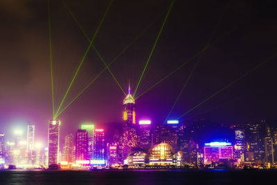 Illuminated modern buildings in city against sky at night