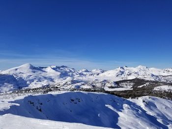 Scenic view of snowcapped mountains against blue sky