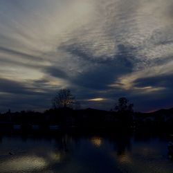 Scenic view of river against cloudy sky at sunset