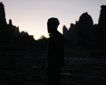 Silhouette man standing on field against sky during sunset