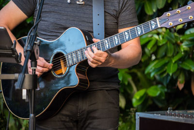 Midsection of man playing guitar