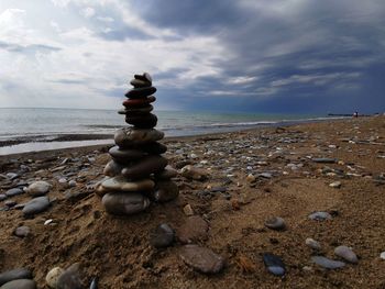 Stack of stones on beach against sky