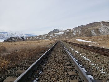 Railroad tracks leading towards mountain against sky