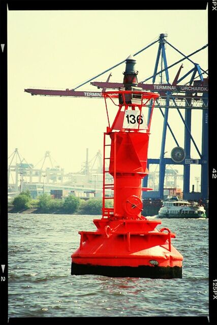 water, red, clear sky, transfer print, transportation, river, mode of transport, nautical vessel, auto post production filter, built structure, waterfront, sea, commercial dock, architecture, harbor, building exterior, sky, outdoors, day, no people