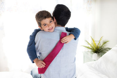 Son huging his father with a necktie on his hands